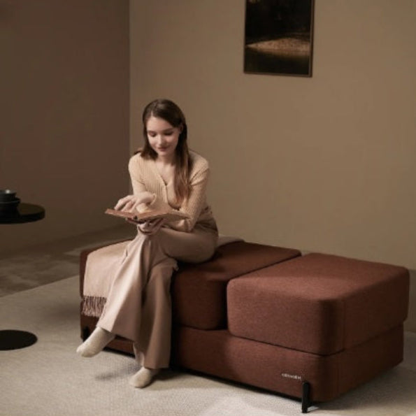 A woman relaxing on a brown Ceragem S4 massage lounger with heat therapy.