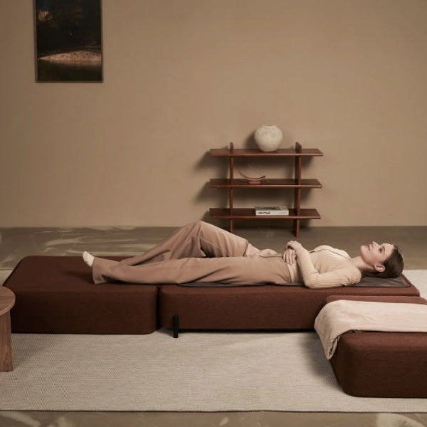 Woman lying on a Ceragem S4 massage lounger in a spa setting with a neutral color palette.
