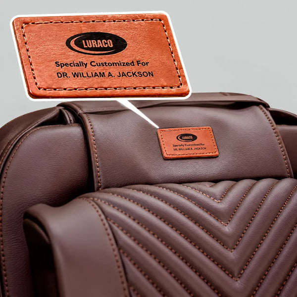 Close-up of the Luraco iRobotics 11 Special Edition Medical Massage Chair in chocolate brown leather, featuring a personalized engraved Luraco badge honoring Dr. William A. Jackson.